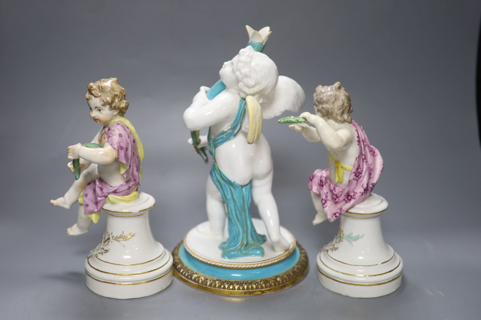 A pair of 19th century Berlin seated cherubs and a Continental porcelain figure of a cherub holding a cornucopia, tallest 27cm